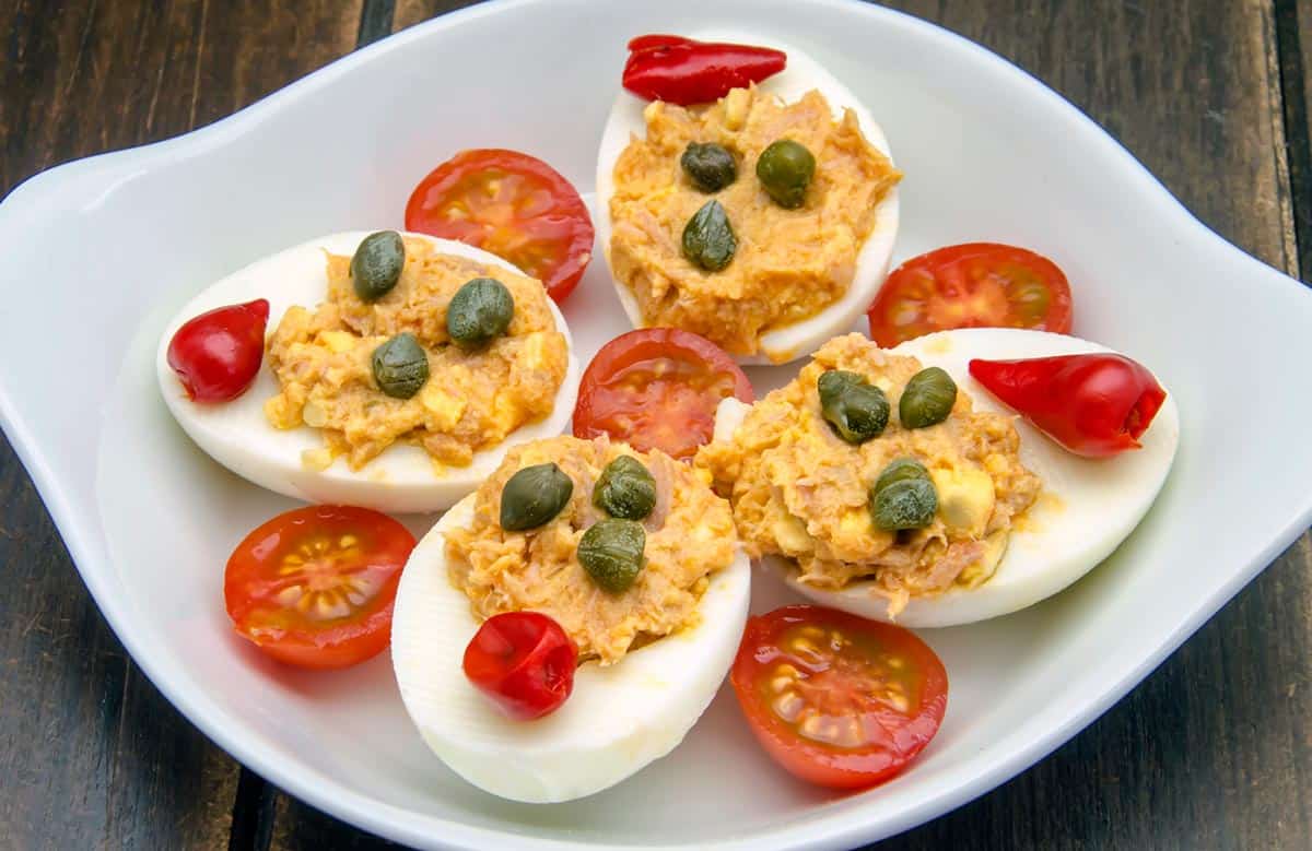 plato con huevos rellenos de atún decoradoc con alcaparras y tomates